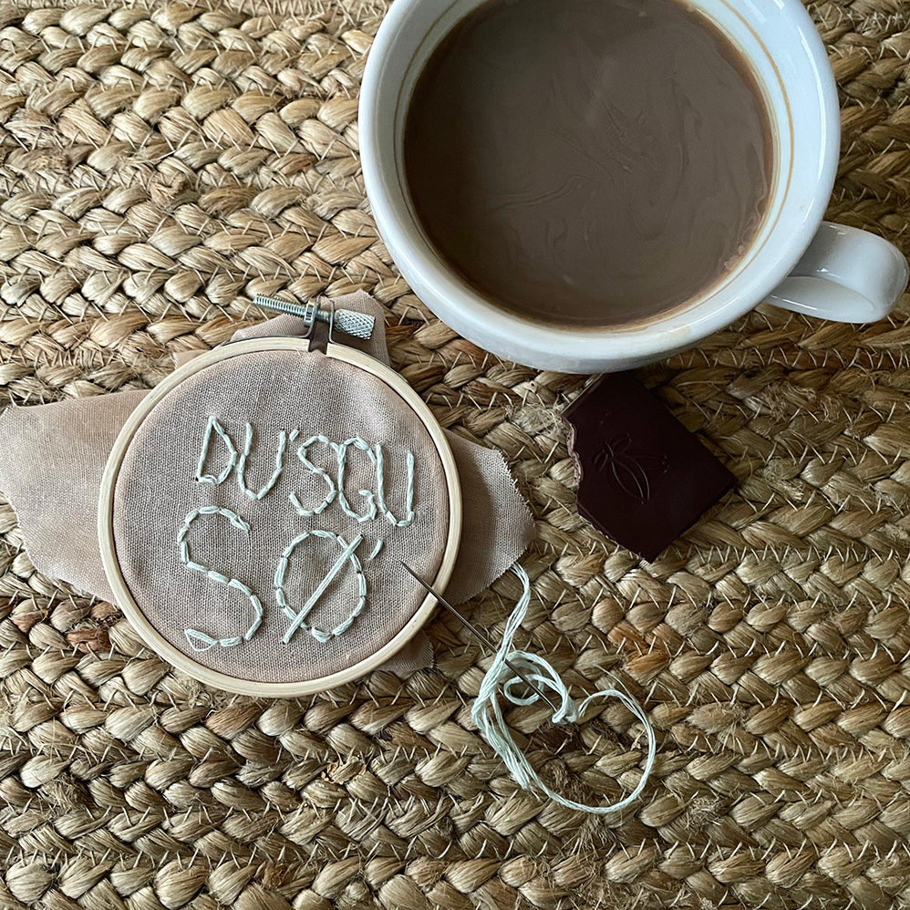 broderi ved siden af kaffekop og chokolade